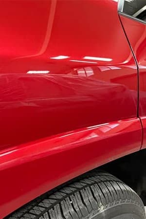 Porta vermelha com riscos superficiais eliminados por paint correction de 2 etapas — after